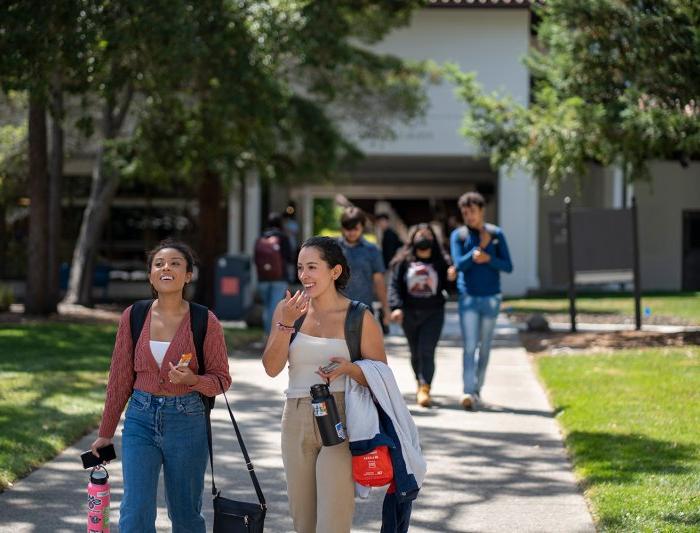 two students are walking through campus as they're chatting